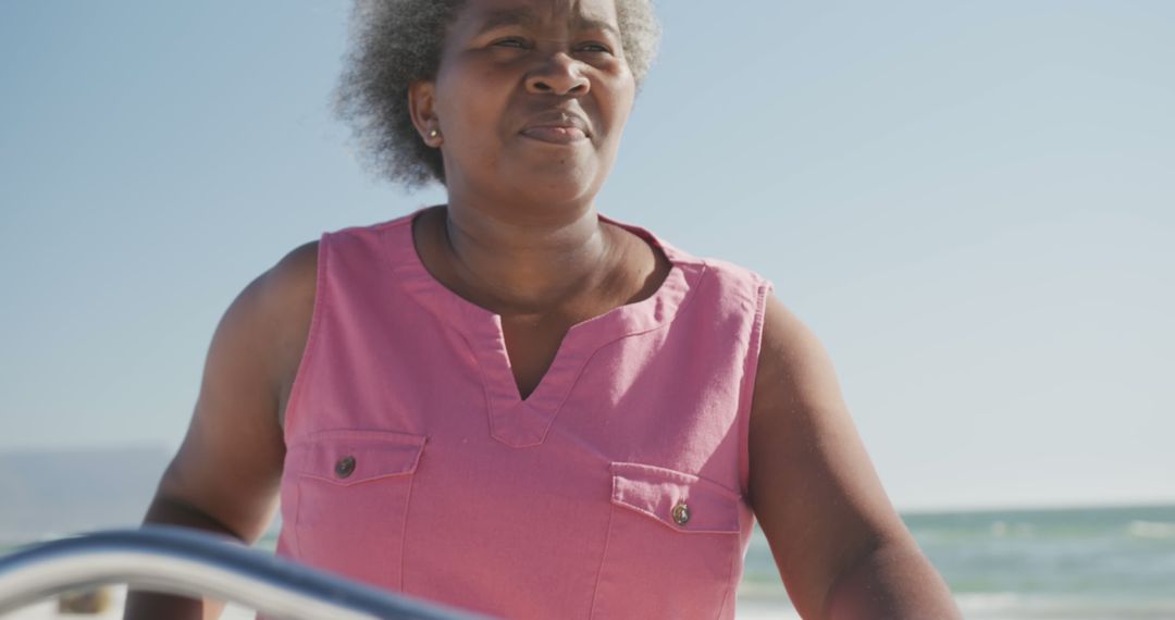 Senior Woman Relaxing at Beach in Pink Blouse Enjoying Sunny Day - Free Images, Stock Photos and Pictures on Pikwizard.com