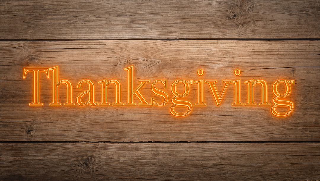 Glowing Neon Thanksgiving Sign Sitting on Rustic Wood Planks with Warm Orange Light