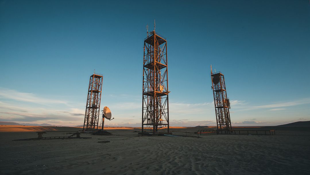 Rustic Communication Towers in Vast Desert at Sunset