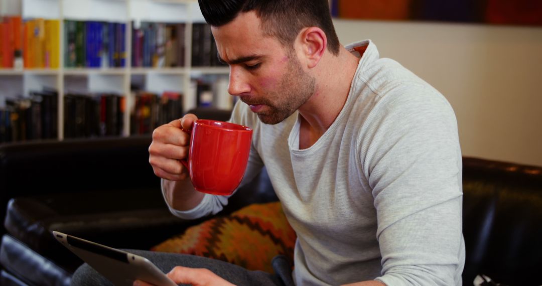 Man Drinking Coffee and Reading on Tablet at Home - Free Images, Stock Photos and Pictures on Pikwizard.com