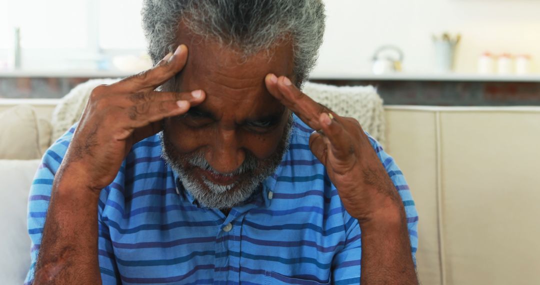 Stressed Senior Man Sitting on Couch Touching Temples - Free Images, Stock Photos and Pictures on Pikwizard.com