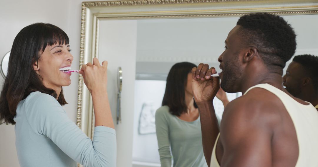 Happy Multiracial Couple Brushing Teeth Together in Bathroom Mirror - Free Images, Stock Photos and Pictures on Pikwizard.com