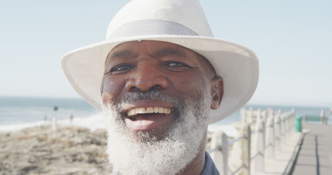 Smiling Elderly Man Enjoying Sunny Day at Beachside - Free Images, Stock Photos and Pictures on Pikwizard.com