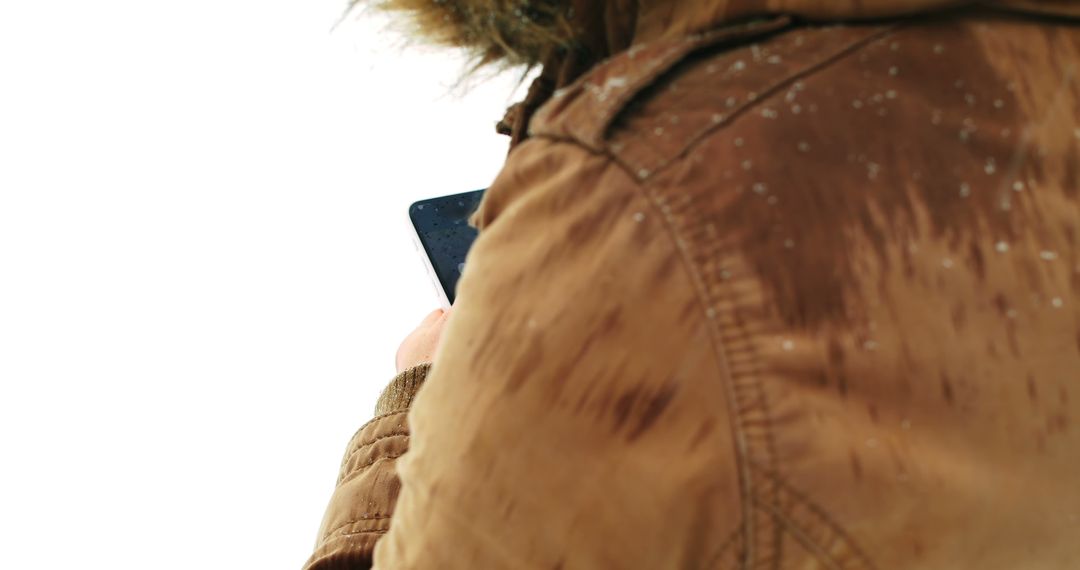 Person Wearing Brown Jacket Using Smartphone in Snowy Weather - Free Images, Stock Photos and Pictures on Pikwizard.com