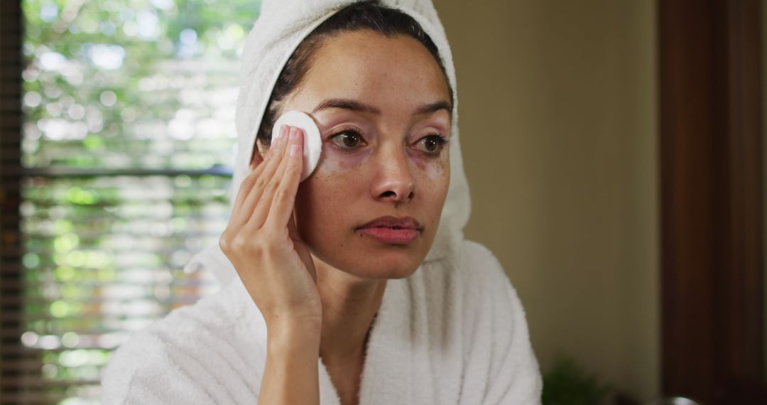 Woman in Bathrobe Cleansing Face with Cotton Pad at Home