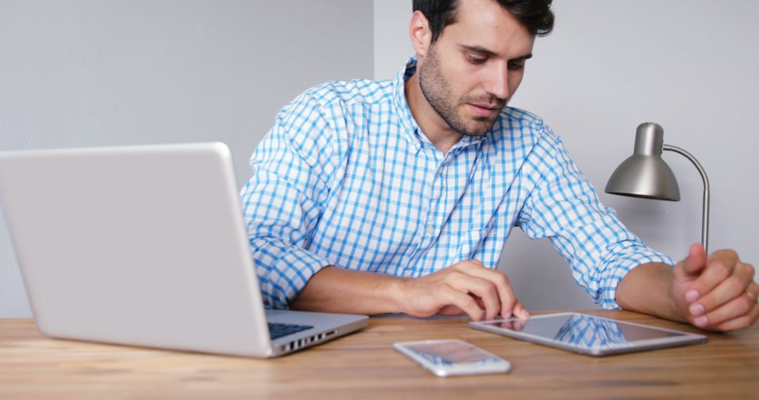 Man Working on Digital Tablet at Desk with Laptop and Smartphone - Free Images, Stock Photos and Pictures on Pikwizard.com