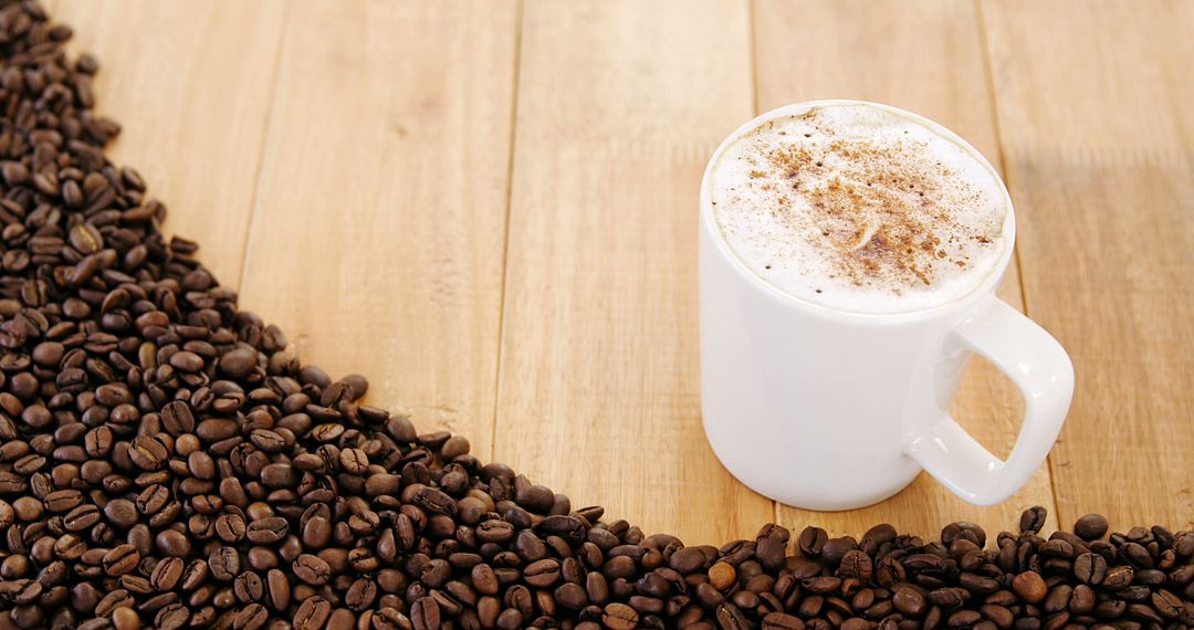 White Mug Filled with Foamy Coffee Surrounded by Coffee Beans on Wooden Table - Free Images, Stock Photos and Pictures on Pikwizard.com