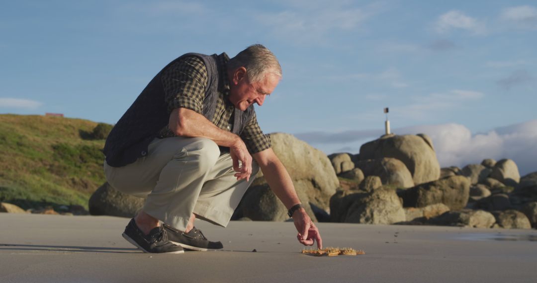 Elderly Man Exploring Beach Collecting Seashells at Sunset - Free Images, Stock Photos and Pictures on Pikwizard.com