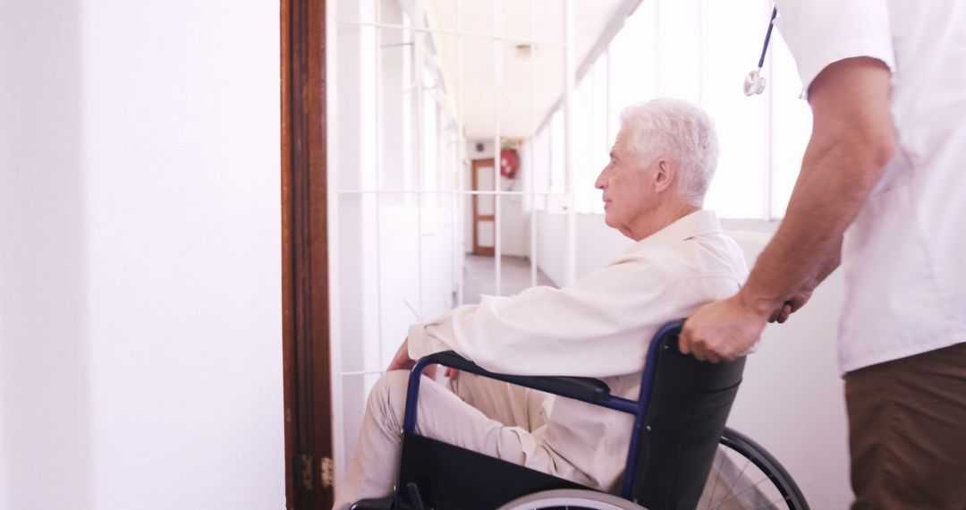 Elderly Man in Wheelchair with Caregiver in Hospital Corridor - Free Images, Stock Photos and Pictures on Pikwizard.com