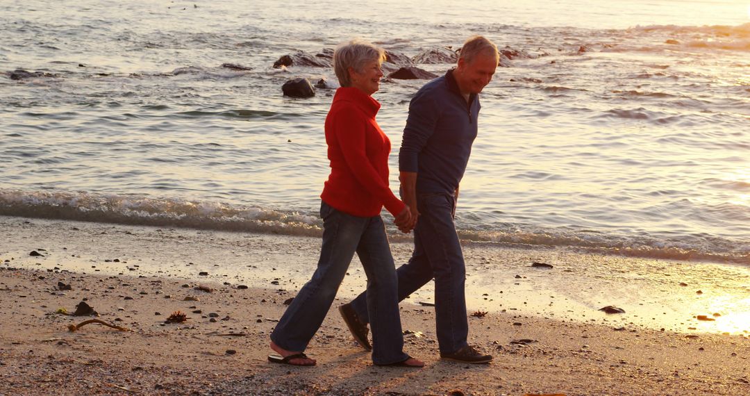 Happy senior caucasian couple holding hands and walking on beach by sea at sunset - Free Images, Stock Photos and Pictures on Pikwizard.com