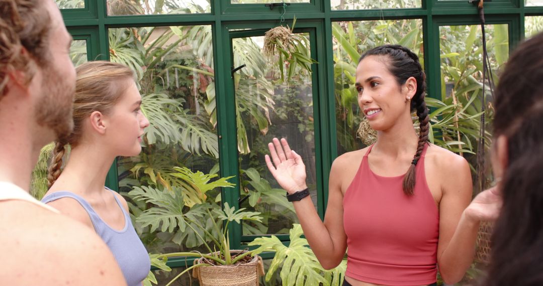 Yoga Class in Glasshouse, Instructor Engaging with Students in Greenery