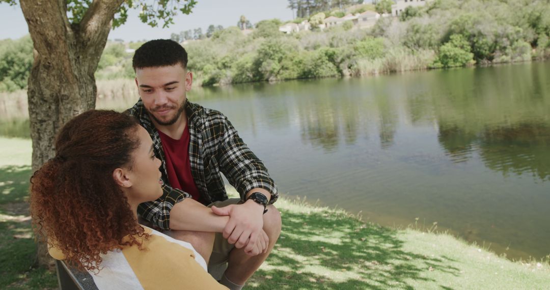 Couple Relaxing by Serene River Under Tree