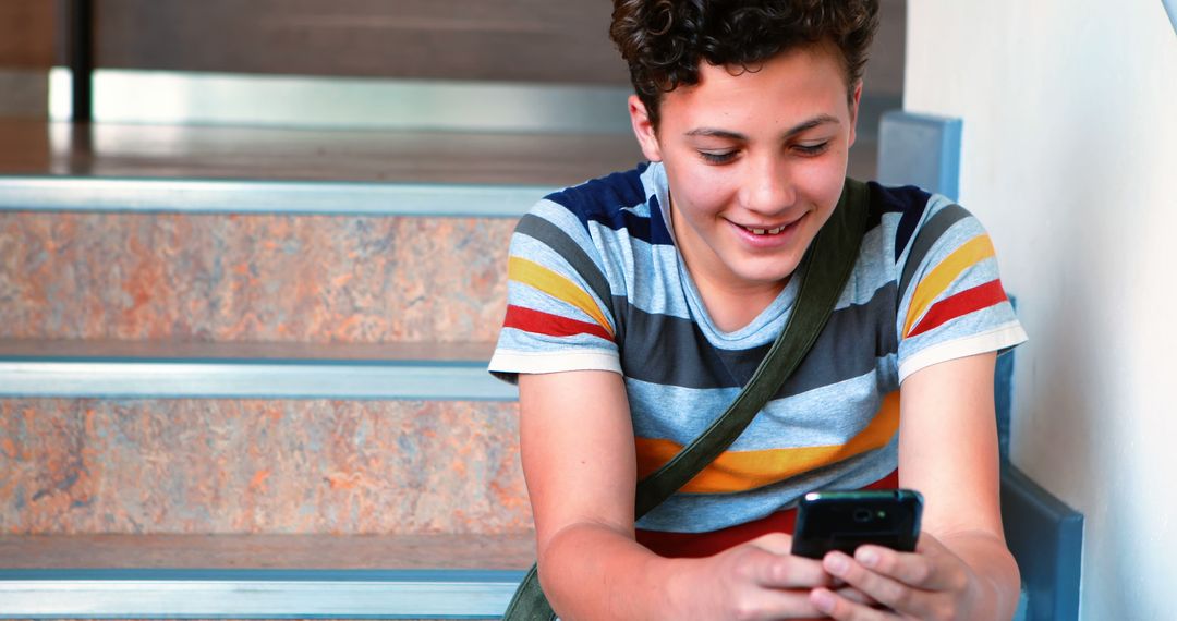 Teenager Smiling and Using Smartphone on Staircase - Free Images, Stock Photos and Pictures on Pikwizard.com