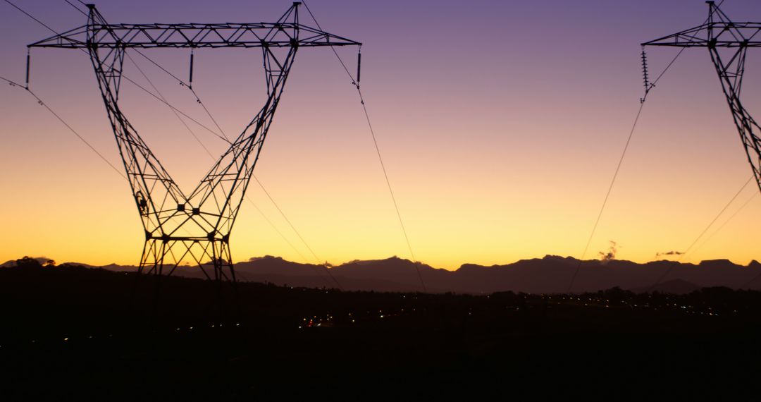 Electricity pylons stand against a twilight sky, silhouetted by the setting sun - Free Images, Stock Photos and Pictures on Pikwizard.com