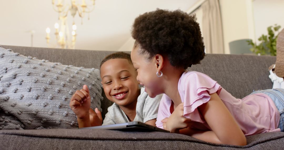 Siblings Relaxing on Sofa Enjoying Screen Time Together