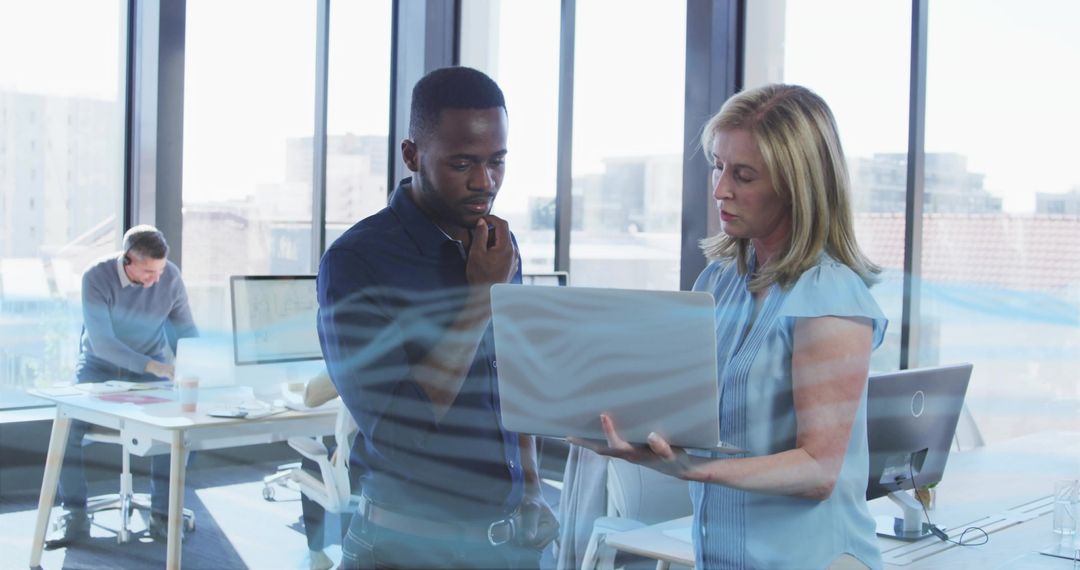 Co-workers Collaborating in Modern Office with Laptops
