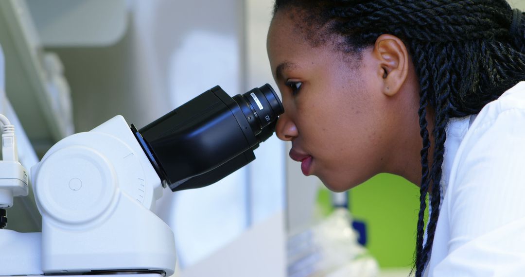 Focused African Scientist Using Microscope in Modern Laboratory