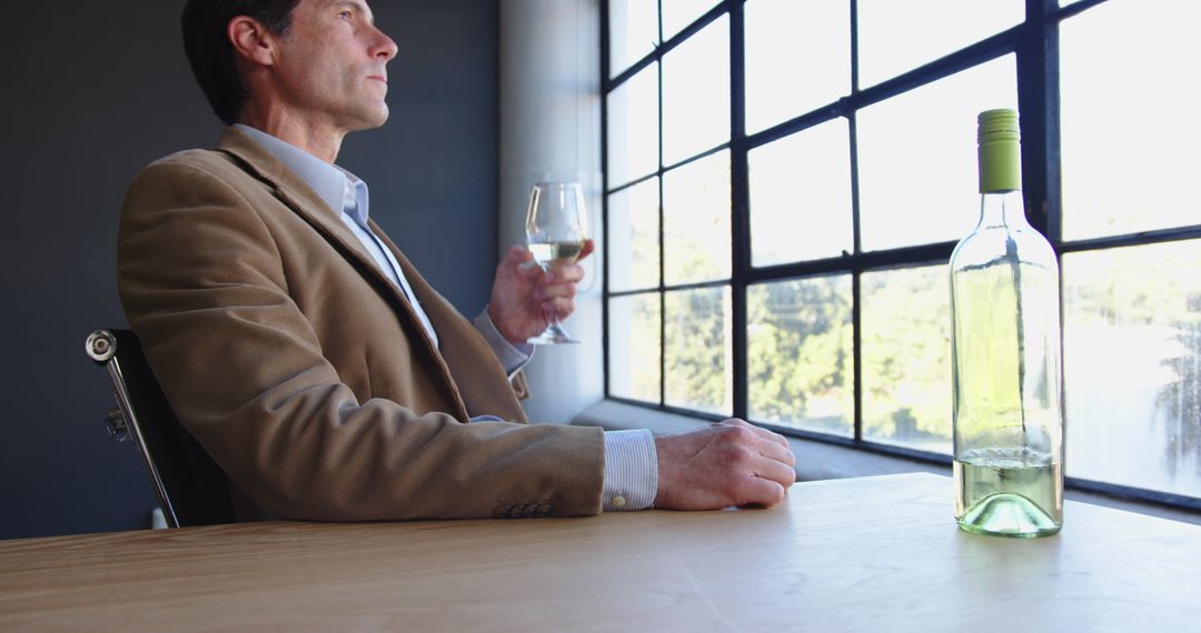 Businessman Enjoying White Wine at Office Desk Near Large Window