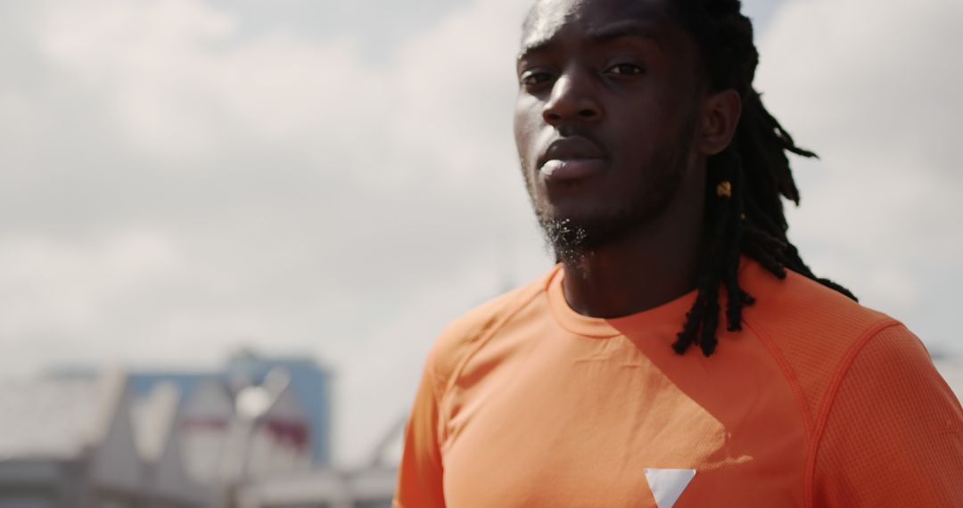 Confident Athlete Wearing Orange Shirt through City Background - Free Images, Stock Photos and Pictures on Pikwizard.com