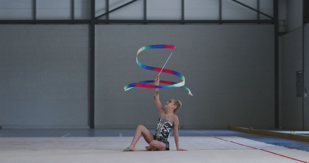 Young Rhythmic Gymnast Performing with Ribbon in Indoor Sports Hall - Free Images, Stock Photos and Pictures on Pikwizard.com