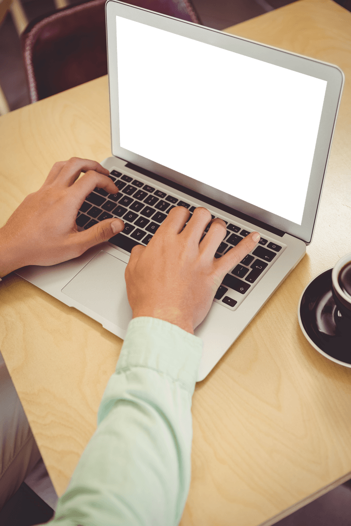 Person Typing on Transparent Laptop in Coffee Shop Setting
