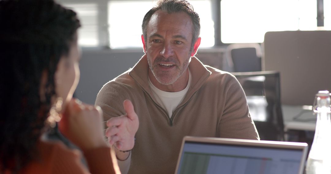 Manager leading one-on-one meeting with diverse colleague over laptop spreadsheet