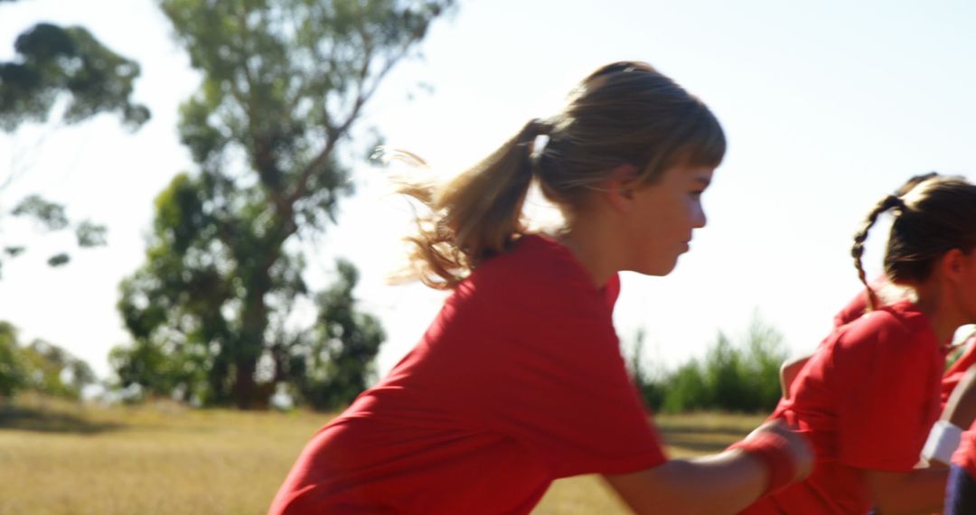 Young girls in red shirts running outdoors on sunny day - Free Images, Stock Photos and Pictures on Pikwizard.com