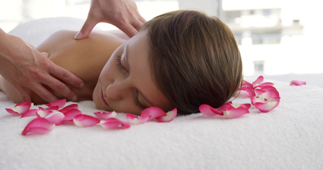 Young woman enjoying relaxing back massage with rose petals - Free Images, Stock Photos and Pictures on Pikwizard.com