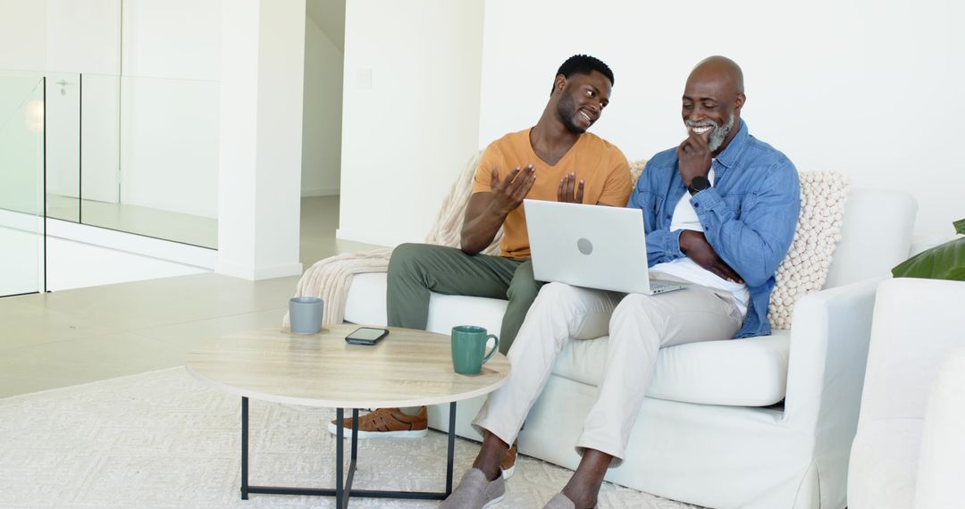 Father and Son Converse While Using Laptop on Cozy Sofa at Home