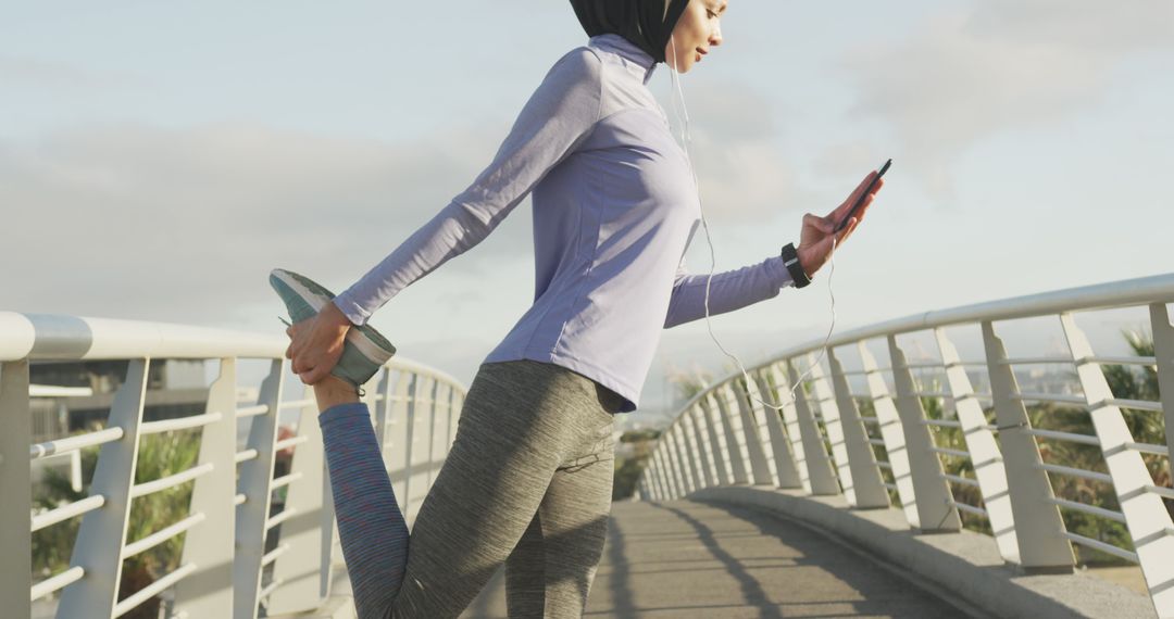 Female Runner Stretching on Urban Bridge While Checking Phone - Free Images, Stock Photos and Pictures on Pikwizard.com