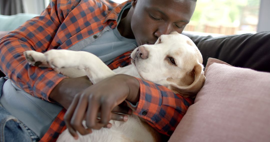 Man Affectionately Kissing Pet Dog While Relaxing at Home