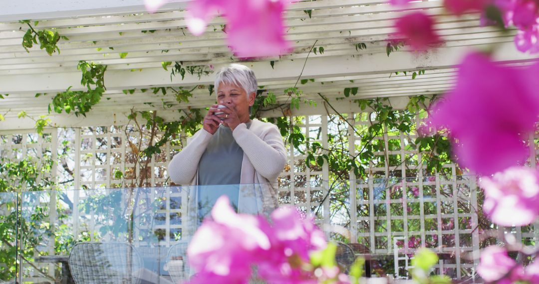 Senior Woman Drinking Coffee in Flower-Filled Garden - Free Images, Stock Photos and Pictures on Pikwizard.com