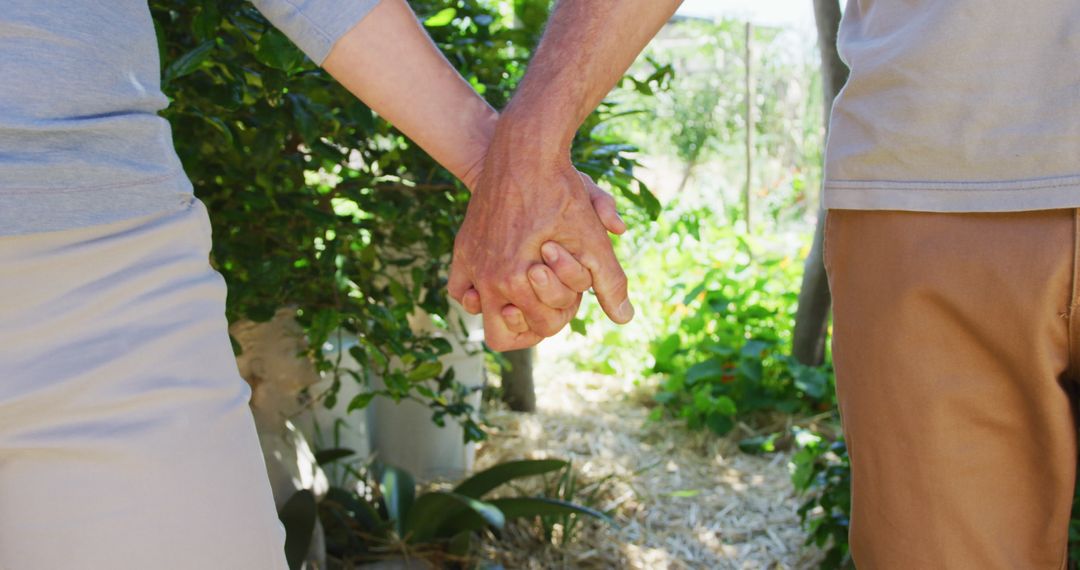 Senior Couple Holding Hands Strolling Through Lush Garden