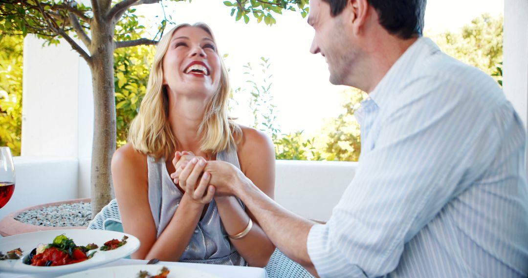 Couple Laughing and Holding Hands at Outdoor Restaurant - Free Images, Stock Photos and Pictures on Pikwizard.com