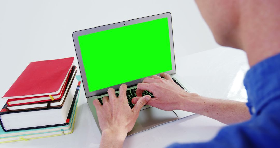 Person working on laptop with green screen at desk - Free Images, Stock Photos and Pictures on Pikwizard.com