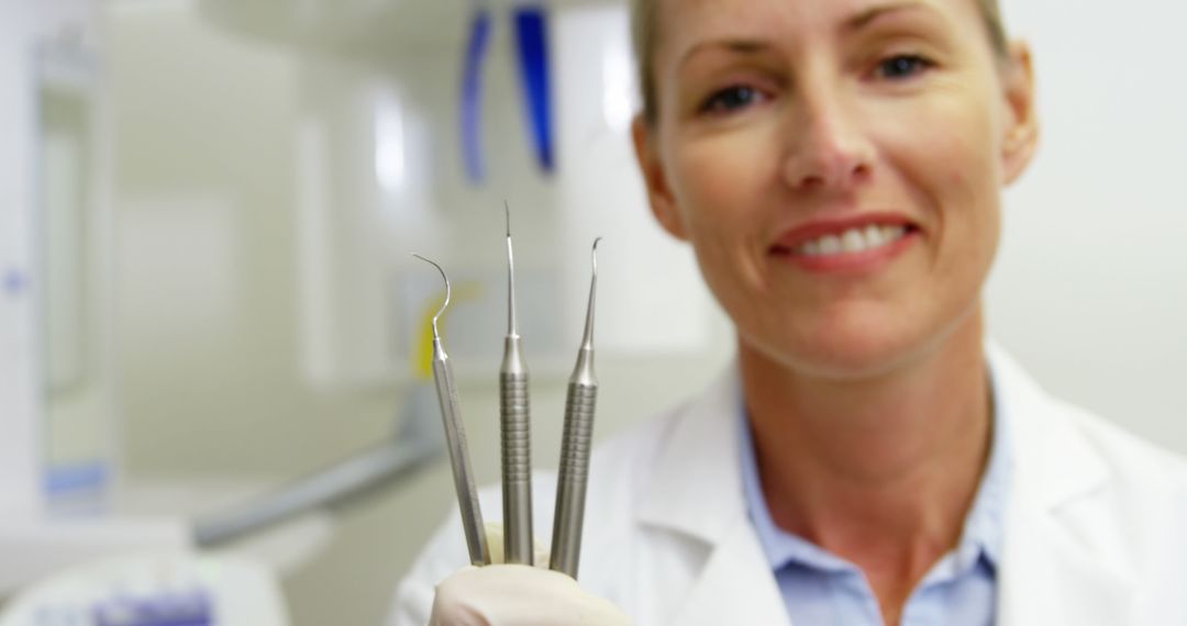 Smiling Dentist Holding Dental Tools in Clinic - Free Images, Stock Photos and Pictures on Pikwizard.com