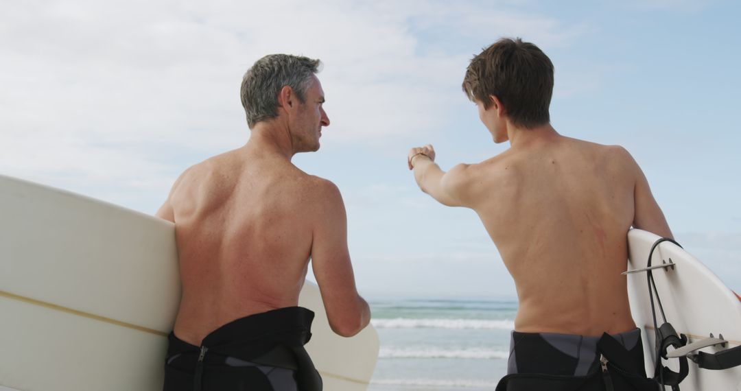 Father and Son Surfers Bonding on Beach Pointing at Ocean - Free Images, Stock Photos and Pictures on Pikwizard.com