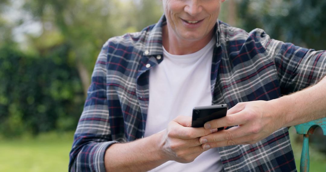 Man Sitting Outdoors Using Smartphone Smiling - Free Images, Stock Photos and Pictures on Pikwizard.com