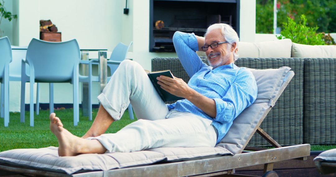 Senior Man Relaxing with Book on Patio Lounger in Garden - Free Images, Stock Photos and Pictures on Pikwizard.com