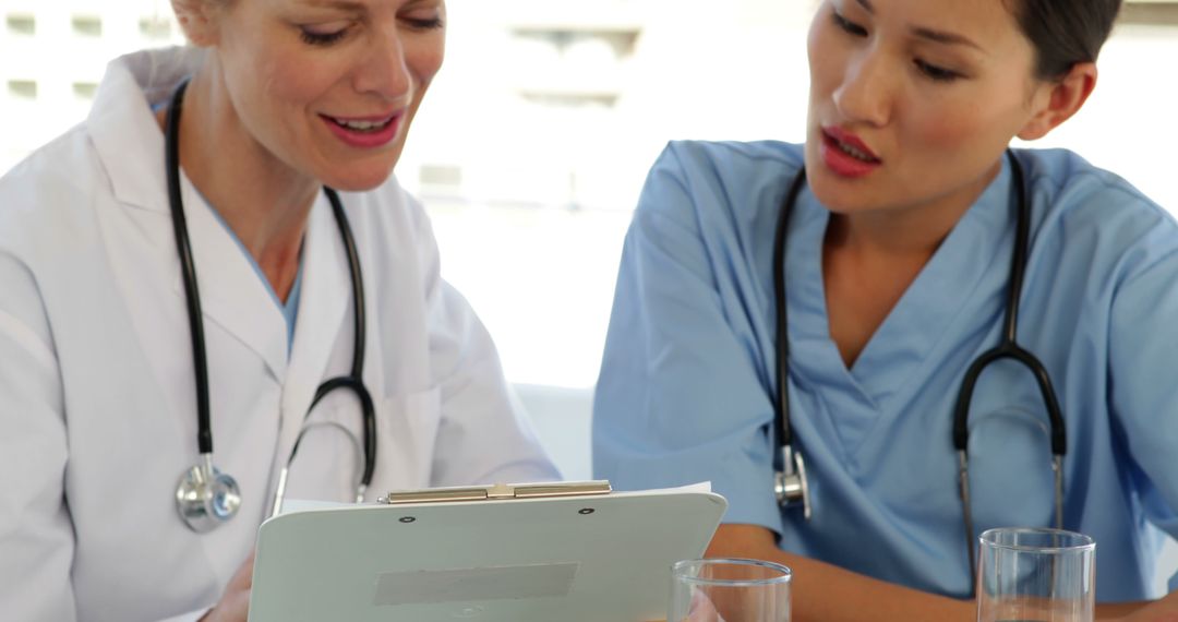 Two Female Doctors Discussing Medical Records in Office - Free Images, Stock Photos and Pictures on Pikwizard.com