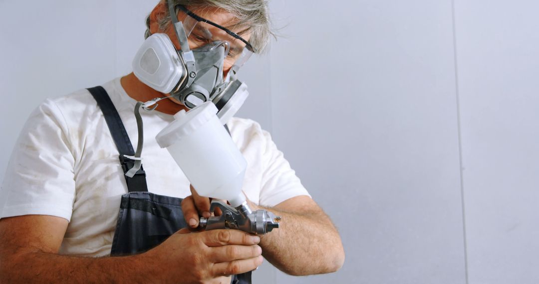 Caucasian man prepares paint sprayer in a workshop - Free Images, Stock Photos and Pictures on Pikwizard.com