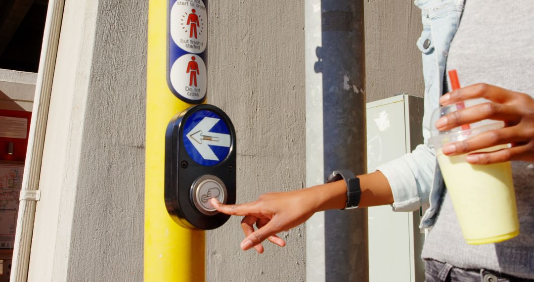 Person Pressing Street Crossing Button While Holding Milkshake