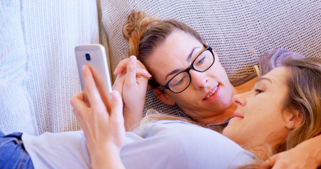 Two Women Relaxing Together on Couch Using Smartphone - Free Images, Stock Photos and Pictures on Pikwizard.com