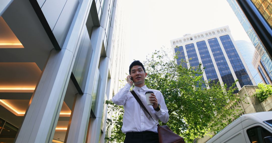 Businessman Talking on Phone Holding Coffee in Urban Setting - Free Images, Stock Photos and Pictures on Pikwizard.com