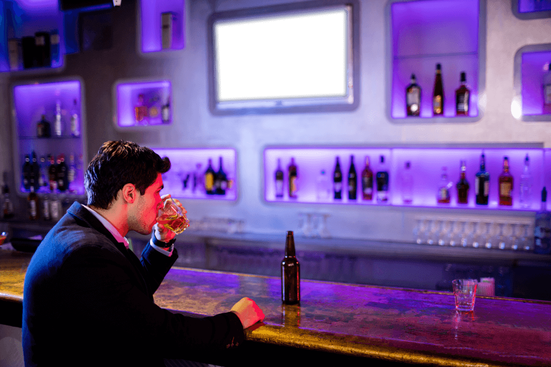 Businessman Sitting at Bar Holding Transparent Drinking Glass
