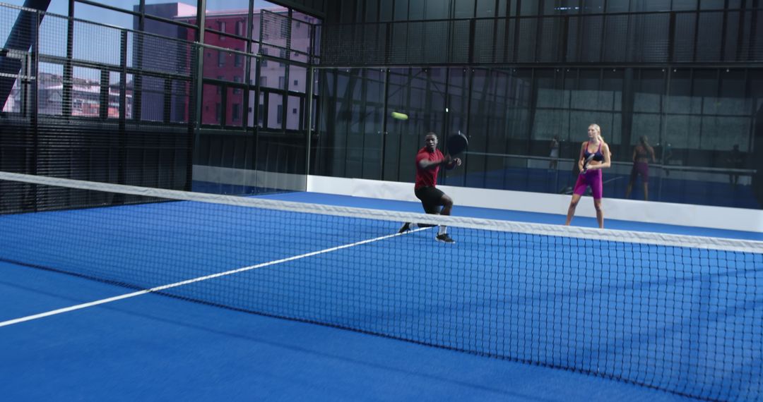 Diverse Teammates Playing Padel on Blue Court with Intensity
