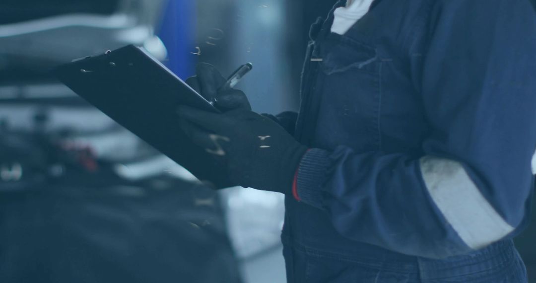 Female mechanic inspecting engine and writing checklist on clipboard in garage workshop