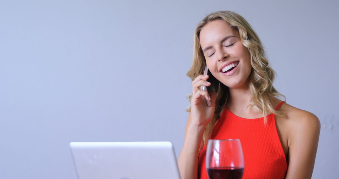 Woman Talking On Phone While Using Laptop With Wine Glass - Free Images, Stock Photos and Pictures on Pikwizard.com