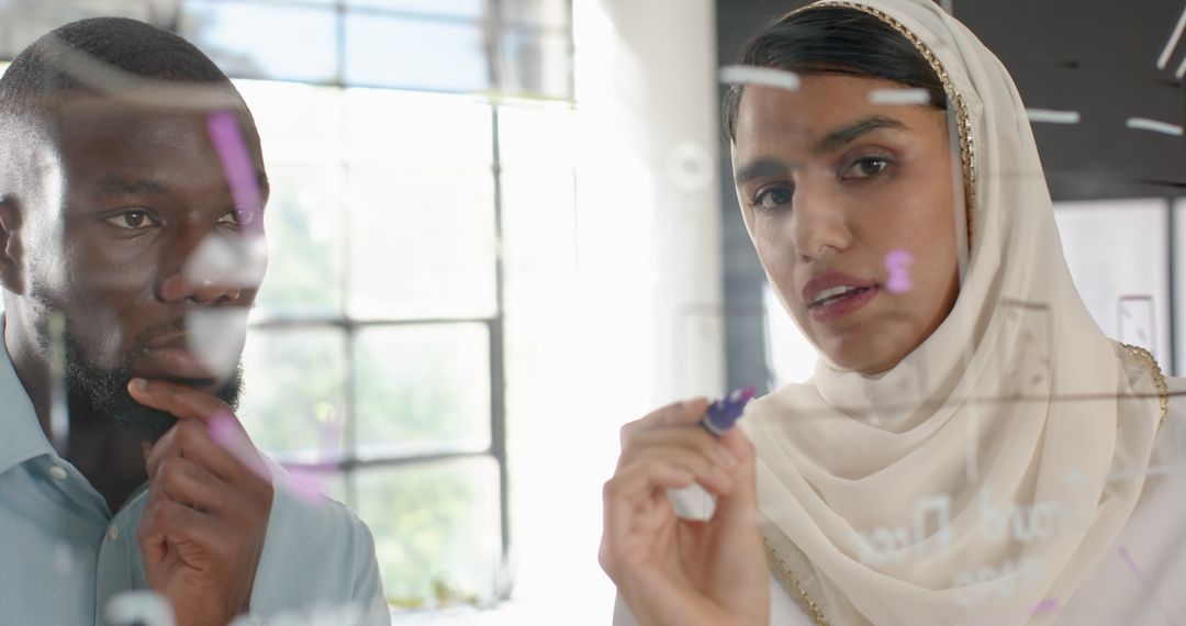 Diverse Team Brainstorming Business Strategy on Glass Board