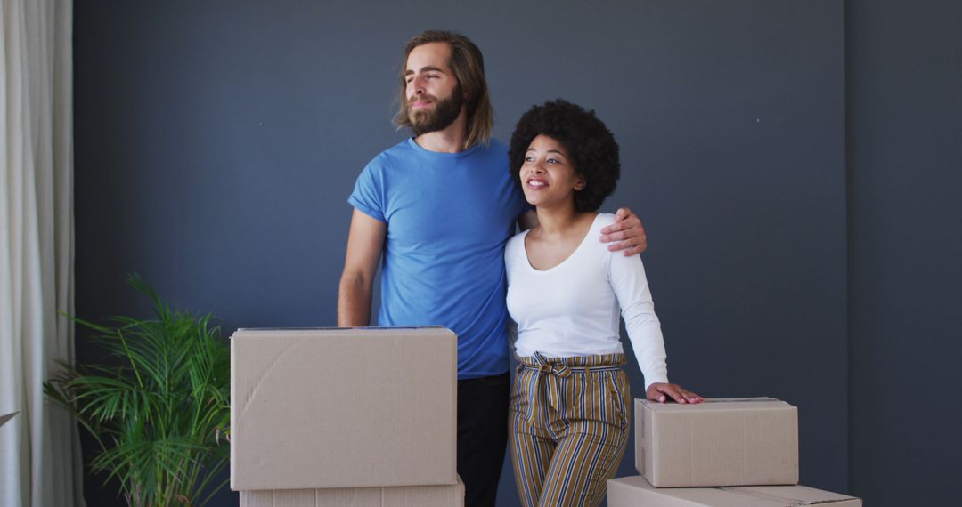 Biracial couple standing in between cardboard boxes at new apartment house - Free Images, Stock Photos and Pictures on Pikwizard.com